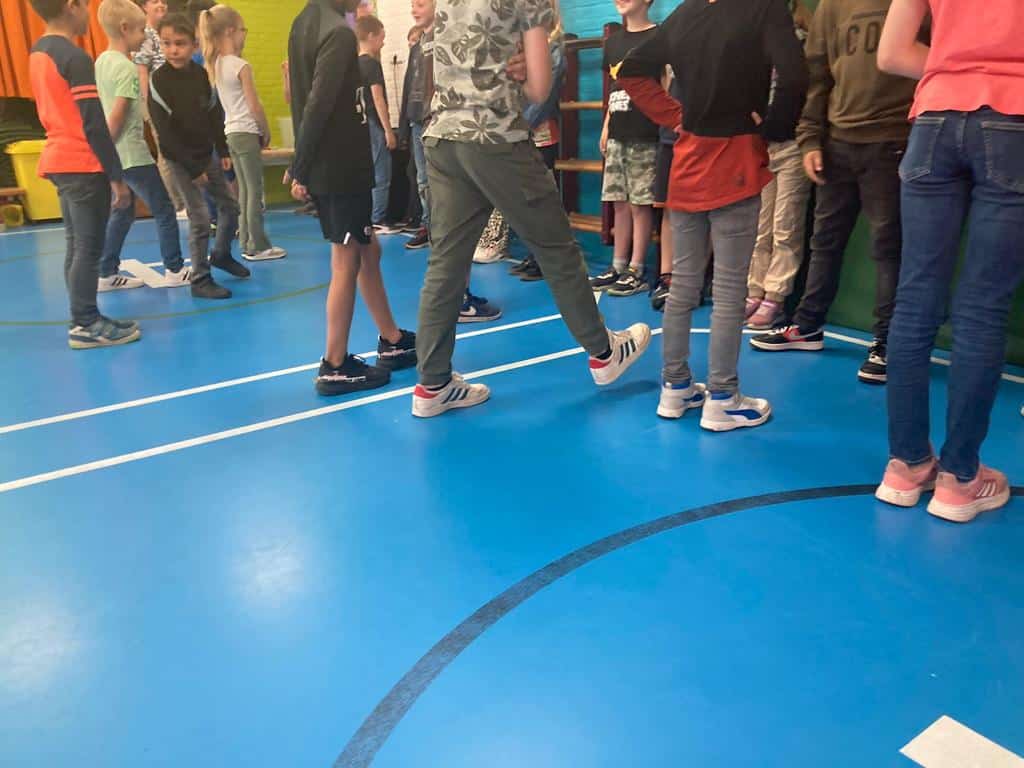 Stap zetten, kr8stroom Benen van leerlingen zichtbaar tijdens een grensoefening, waarbij ze fysiek ervaren waar hun persoonlijke ruimte begint en eindigt.