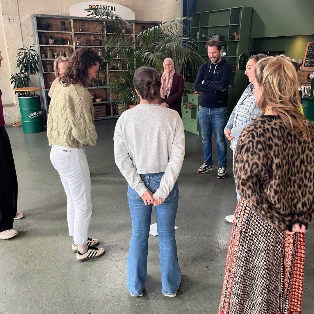 opstelling- vrouw buigt, Kr8stroom Deelnemers staan in een kring tijdens een organisatieopstelling in een grote ruimte.